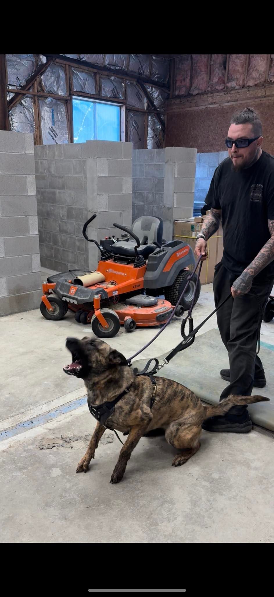 A man is walking a dog on a leash in a garage.
