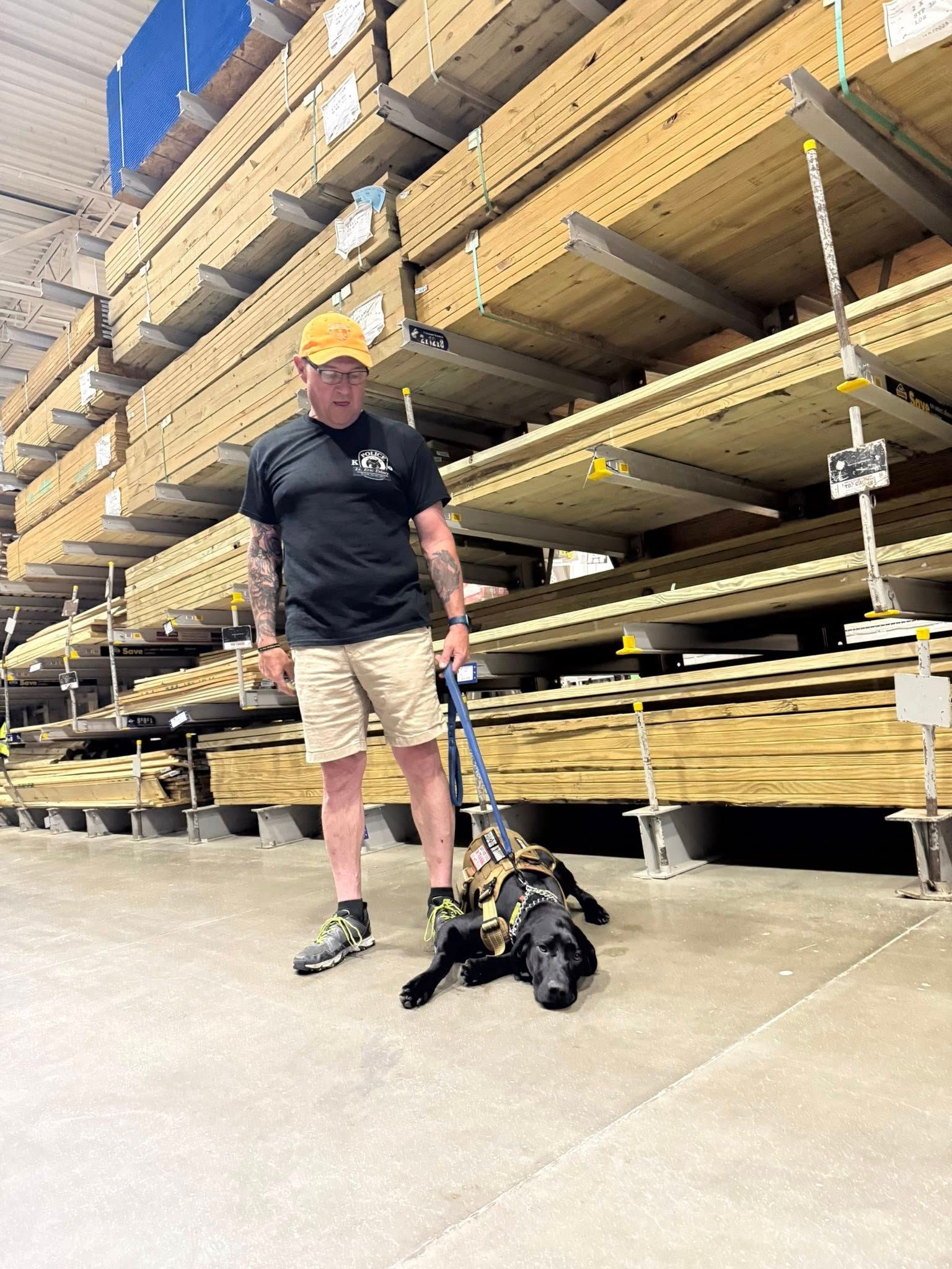 A man is standing in a warehouse with a dog on a leash.