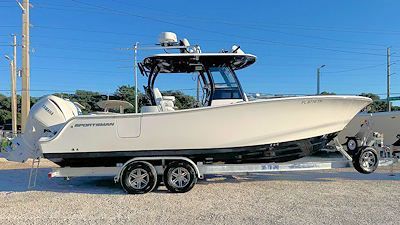 A white center console boat on a trailer, under a clear sky.