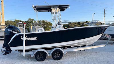 A dark blue and white center console boat on a trailer, parked outside.