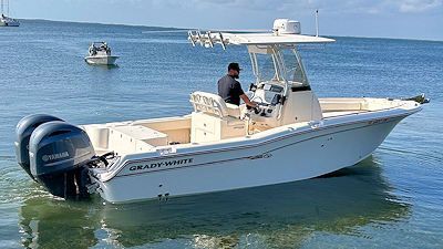 A man pilots a Grady-White boat on the water. It has two Yamaha engines and a white hull.