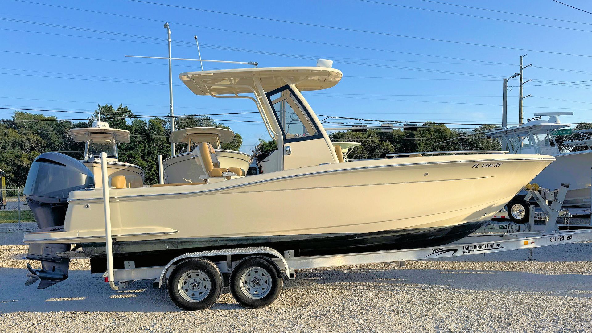 White center-console fishing boat on a trailer in a parking lot under a clear sky