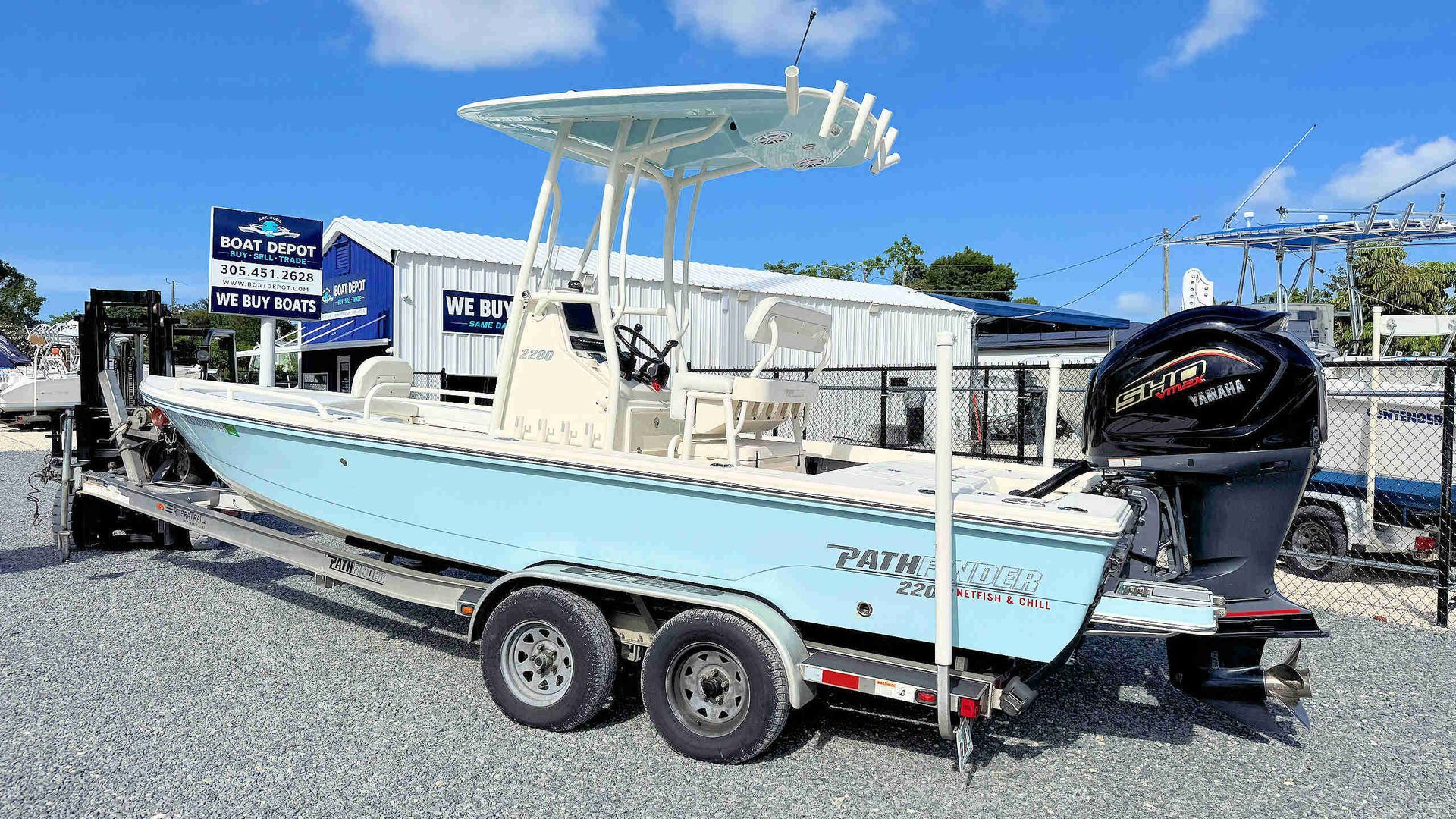 Light blue fishing boat on trailer with T-top, docked in sunny marina