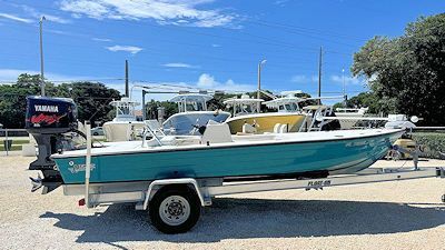 A blue boat is parked on a trailer in a parking lot.