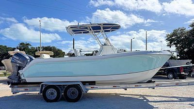 A light blue and white motorboat on a trailer, under a partly cloudy sky.