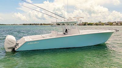 A light blue fishing boat in clear, shallow water.