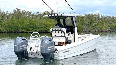White motorboat with two Yamaha engines and fishing gear. Person at the helm, in a watery setting.