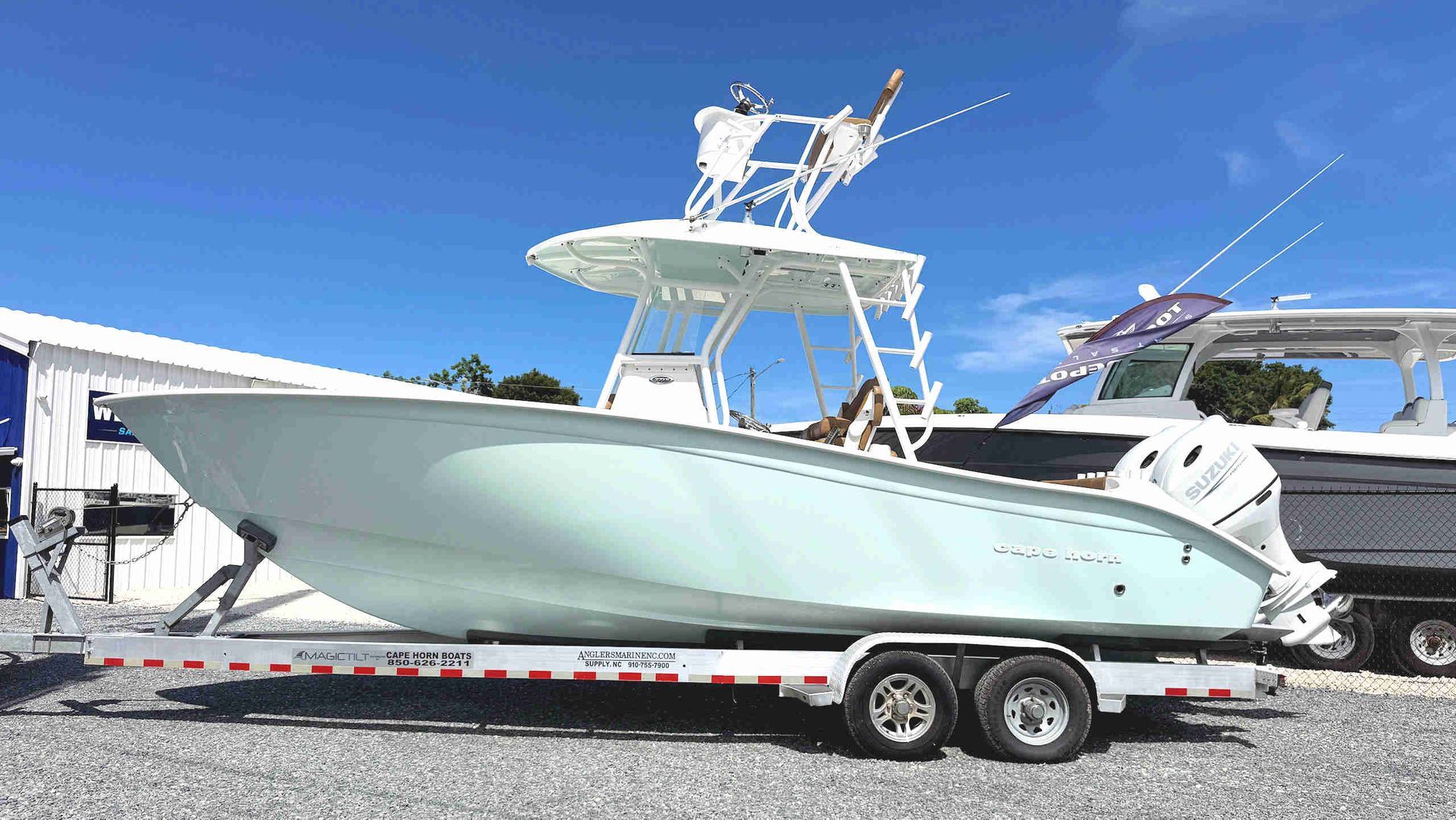 Light green Cape Horn center-console boat on a trailer in a boatyard under a blue sky