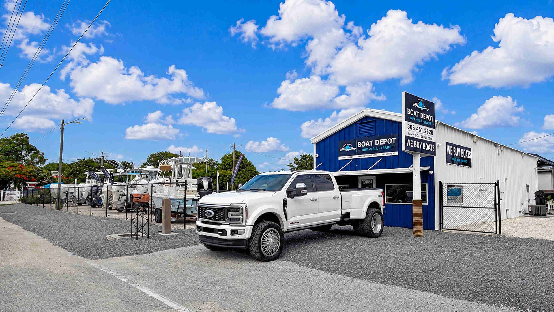 White truck parked outside a blue-and-white auto shop under a bright cloudy sky.
