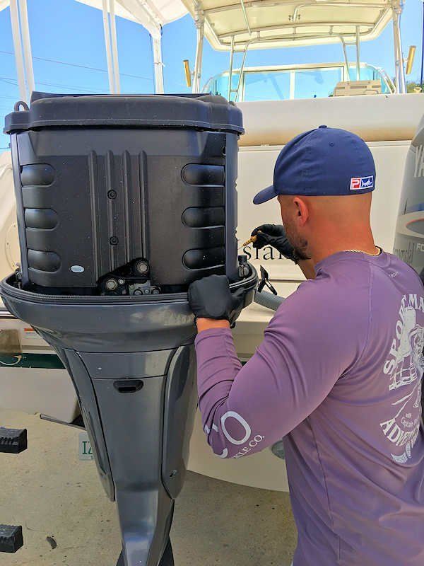 A man in a purple shirt is working on a boat engine.