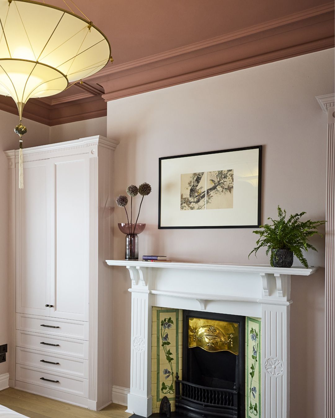 Bedroom detail designed by Michelle Burnett of Cush Interiors featuring an oriental style silk chandelier  and Edwardian fireplace with built in wardrobes surrounding it painted in blush pink with a morrocan kasbah colour on the ceiling