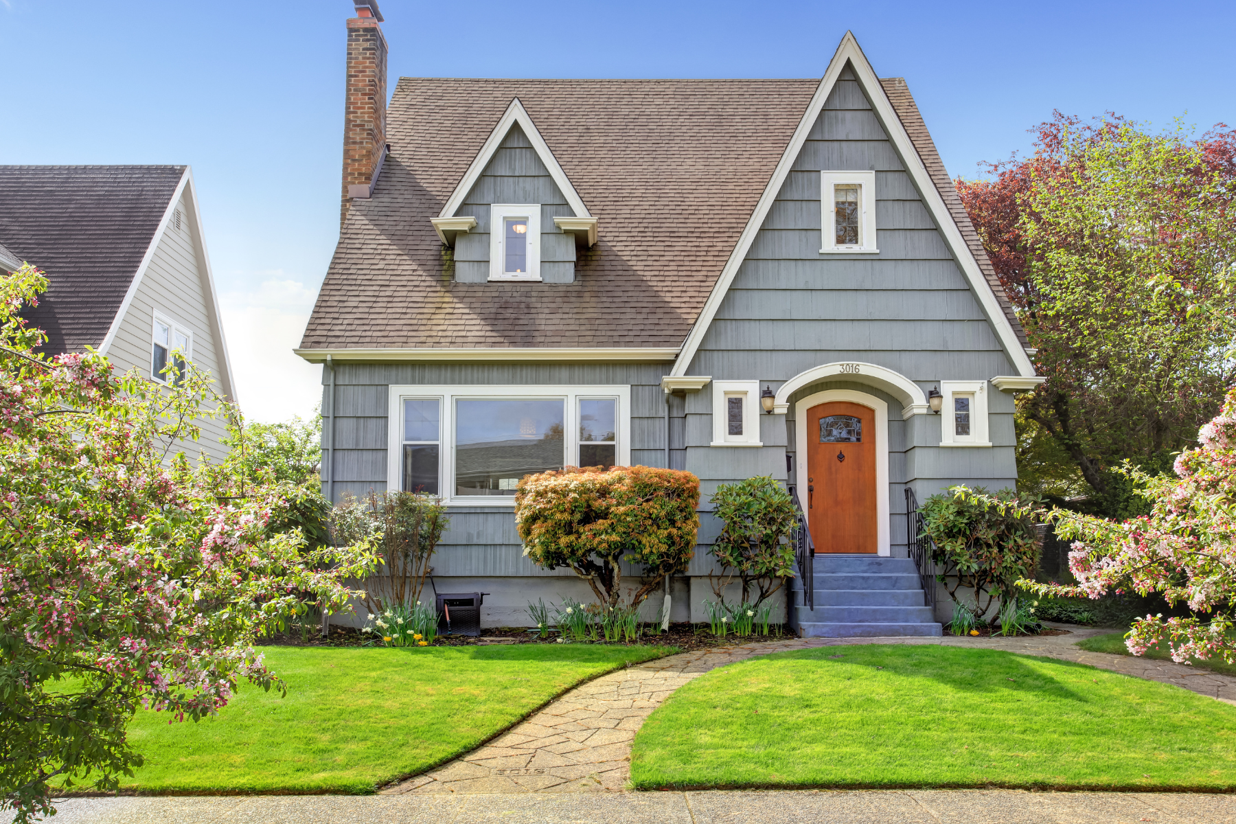 Little blue house with a red door and a green lawn