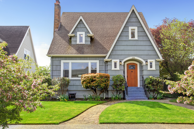 Little blue house with a red door and a green lawn