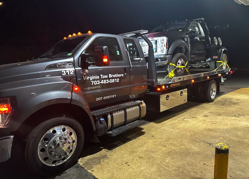 A tow truck is carrying a truck on the back of it.