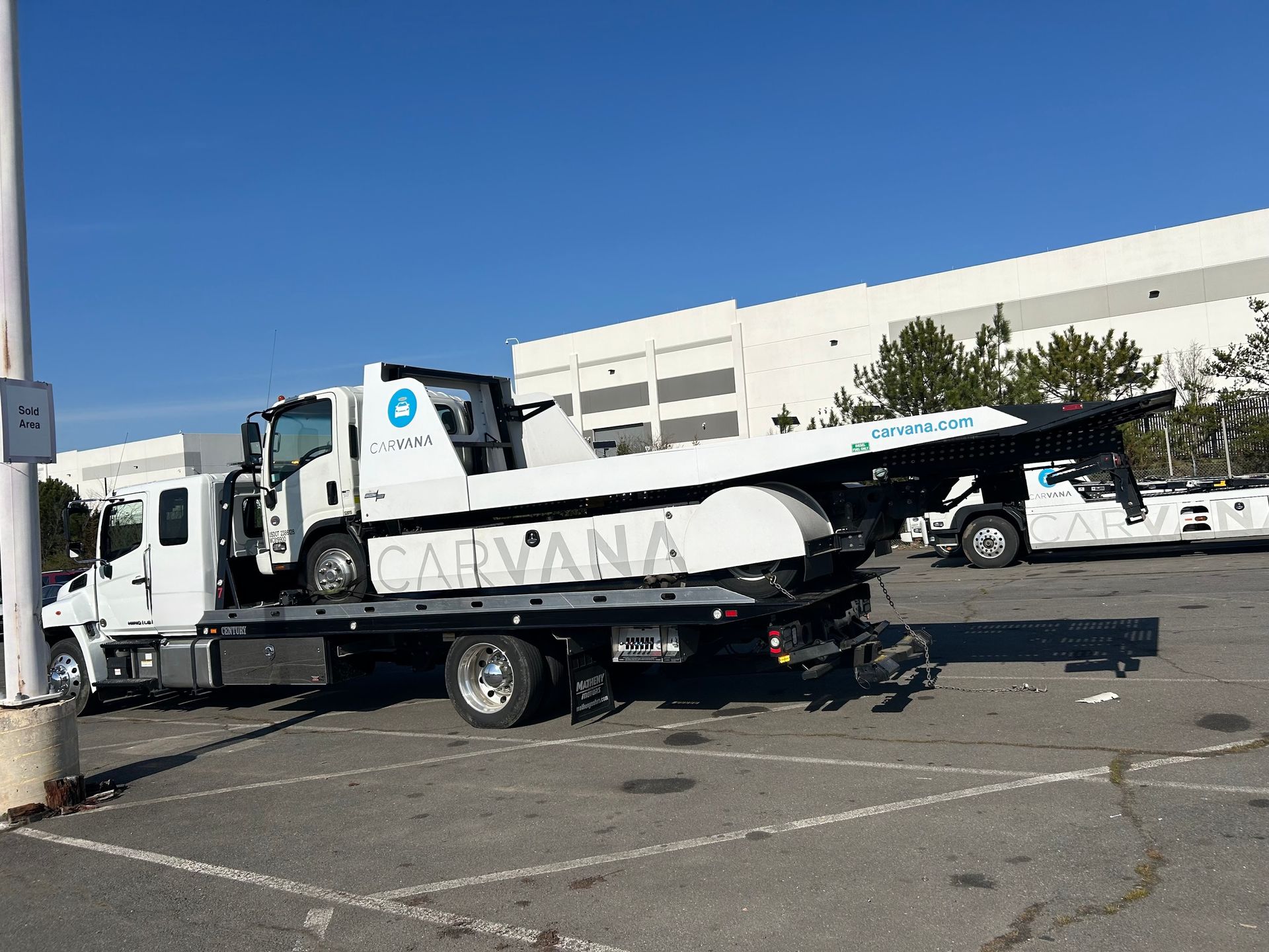 A tow truck with a car on the back is parked in a parking lot.