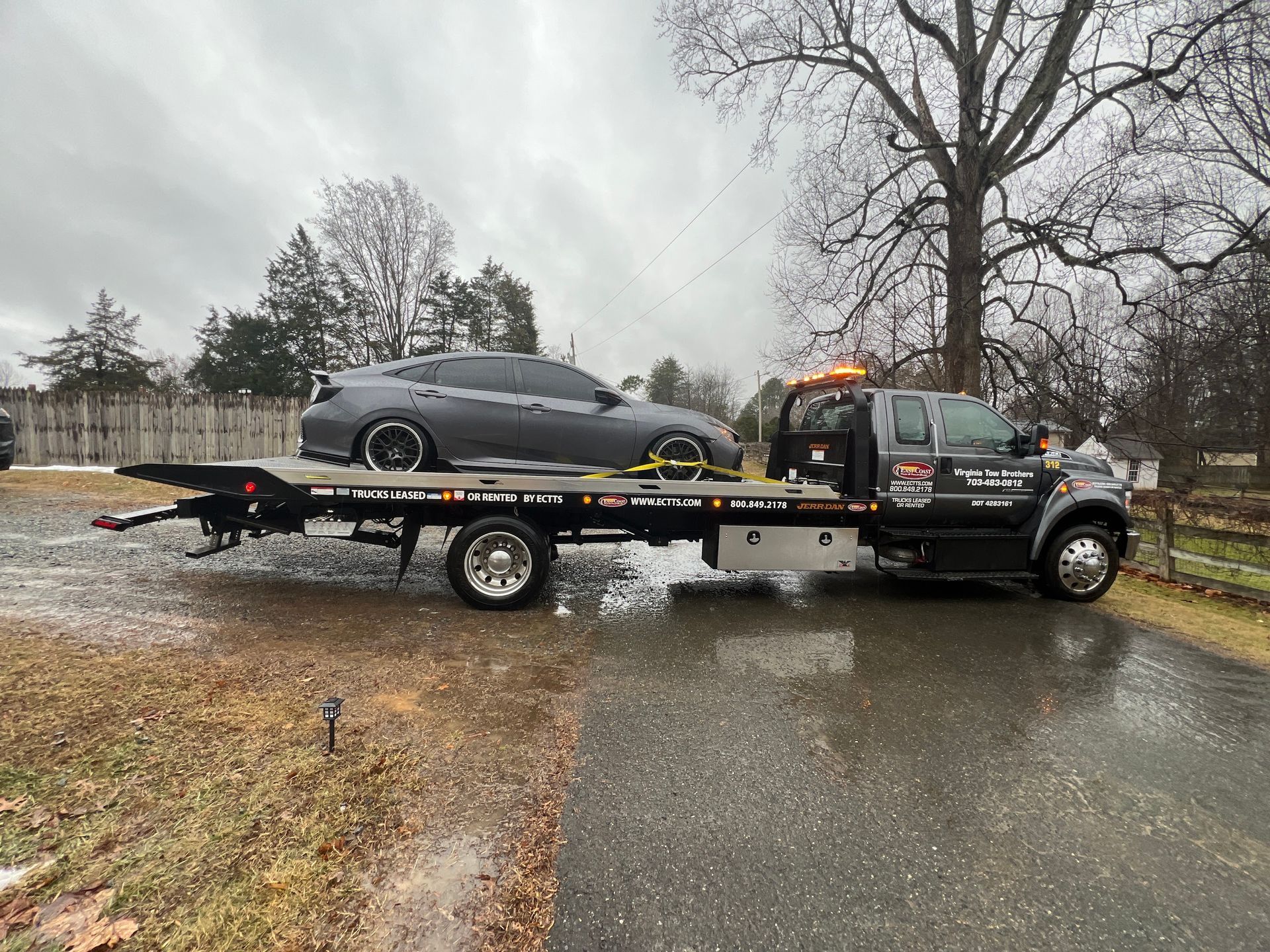 A tow truck is carrying a car on the back of it.