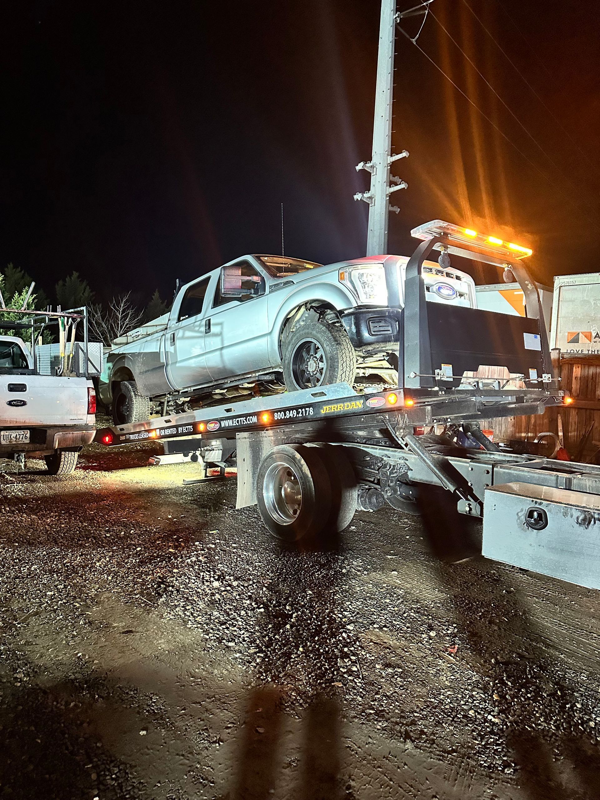 A truck is being towed by a tow truck at night.