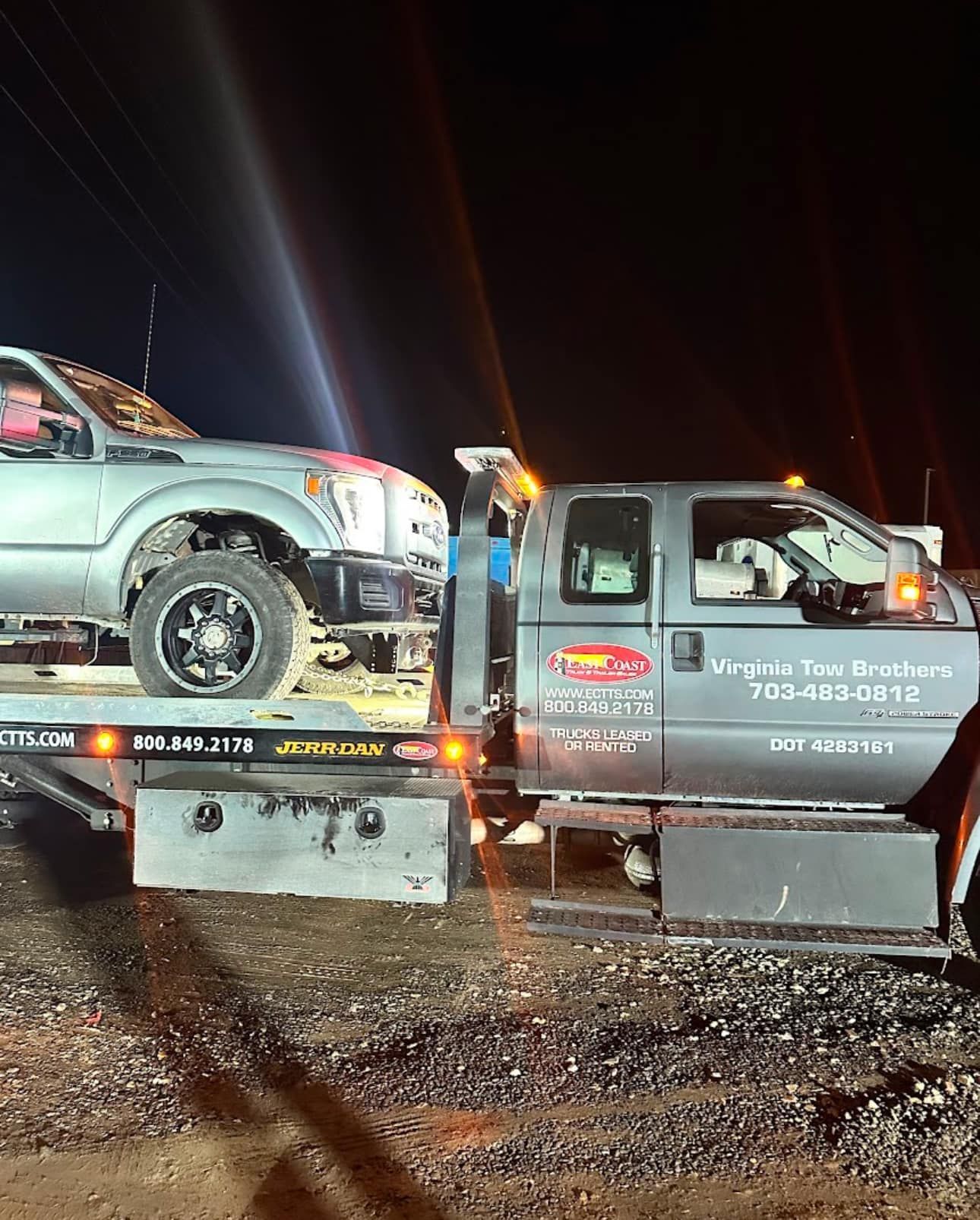A tow truck is carrying a car on the back of it.