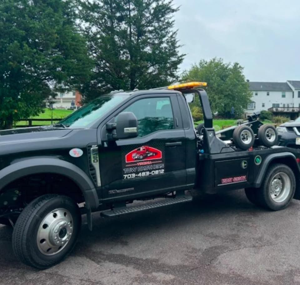 A black tow truck is parked in a parking lot