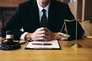 A lawyer is sitting at a desk with a gavel and scales of justice.