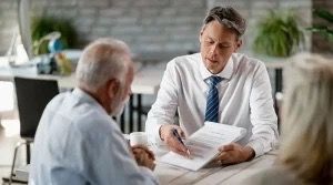 A man is sitting at a table talking to two older men.