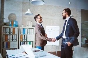 Two men are shaking hands in an office.