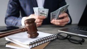 A man in a suit is holding a gavel and a bunch of money.