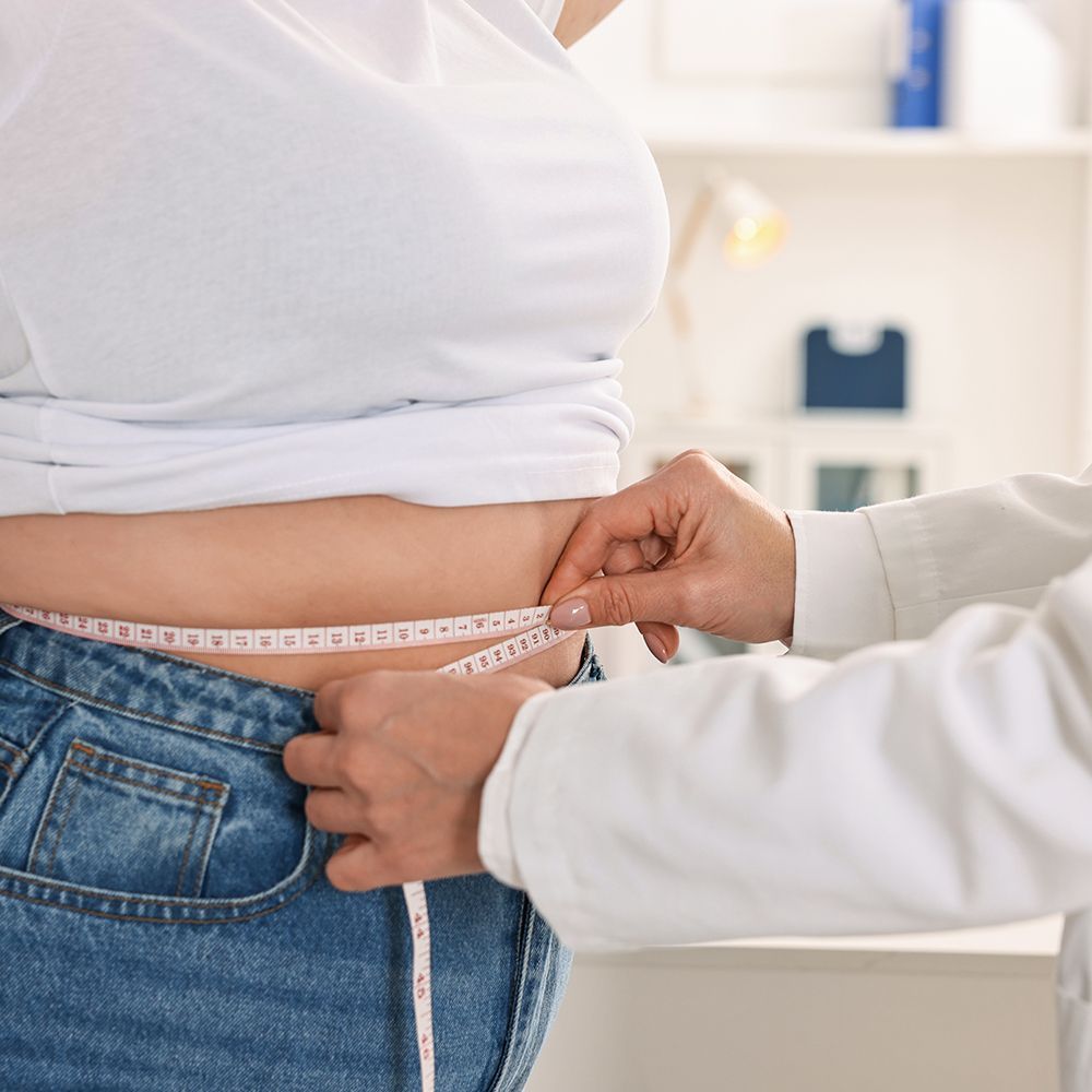 Person receiving intravenous fluids. Medical staff, gloved hands; arm on pillow with IV line and bandage.