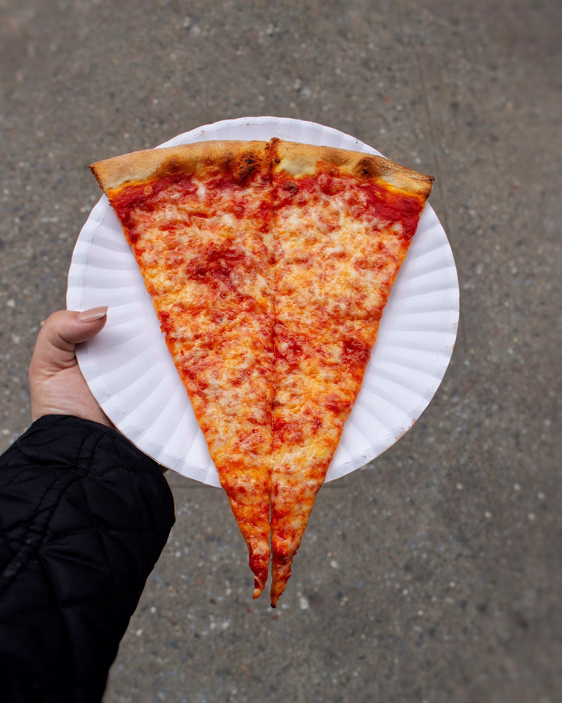 Slice of New York Style pizza with a crispy crust, tomato sauce and melted mozzarella cheese
