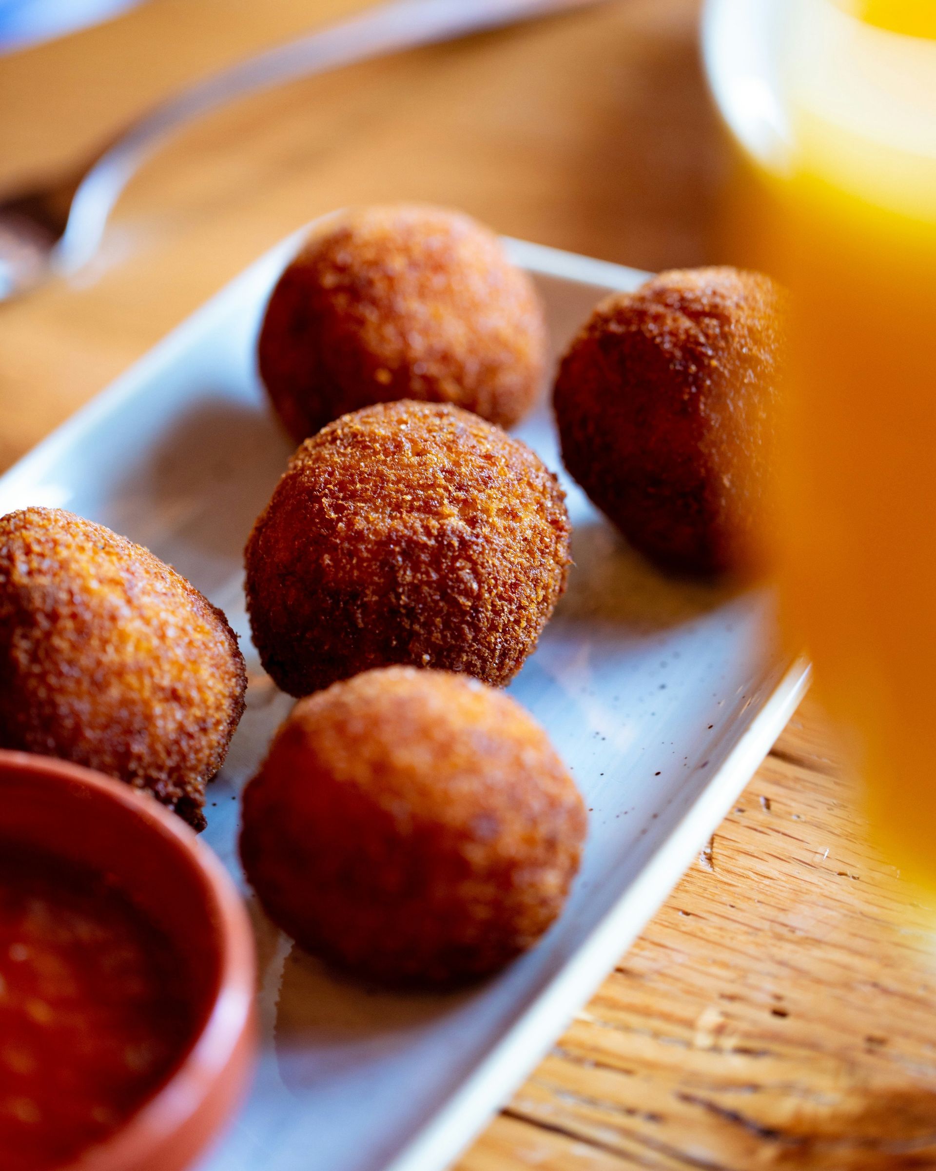 Five fried arancini rice balls served with a side of tomato sauce.