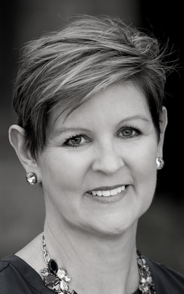 A woman with short hair is smiling in a black and white photo.