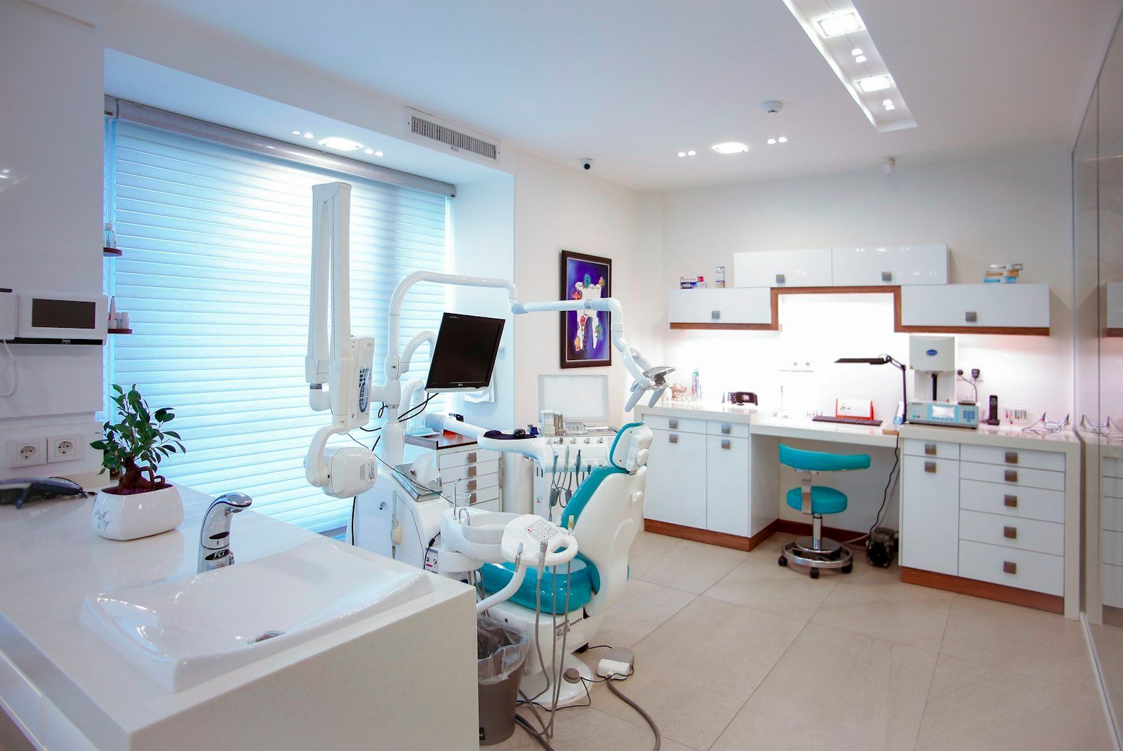 Bright modern dental clinic with chair, equipment, cabinets, and large window blinds