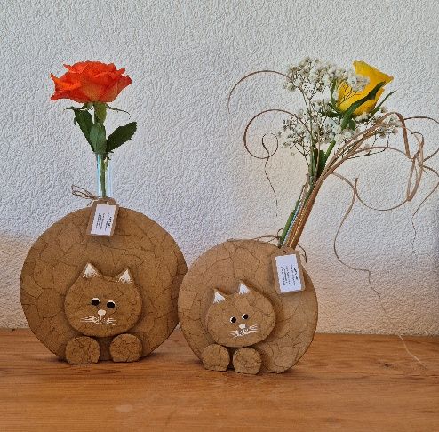 Zwei katzenförmige Vasen mit Blumen. In der einen befindet sich eine orange Rose, in der anderen eine gelbe Rose und weiße Blumen.