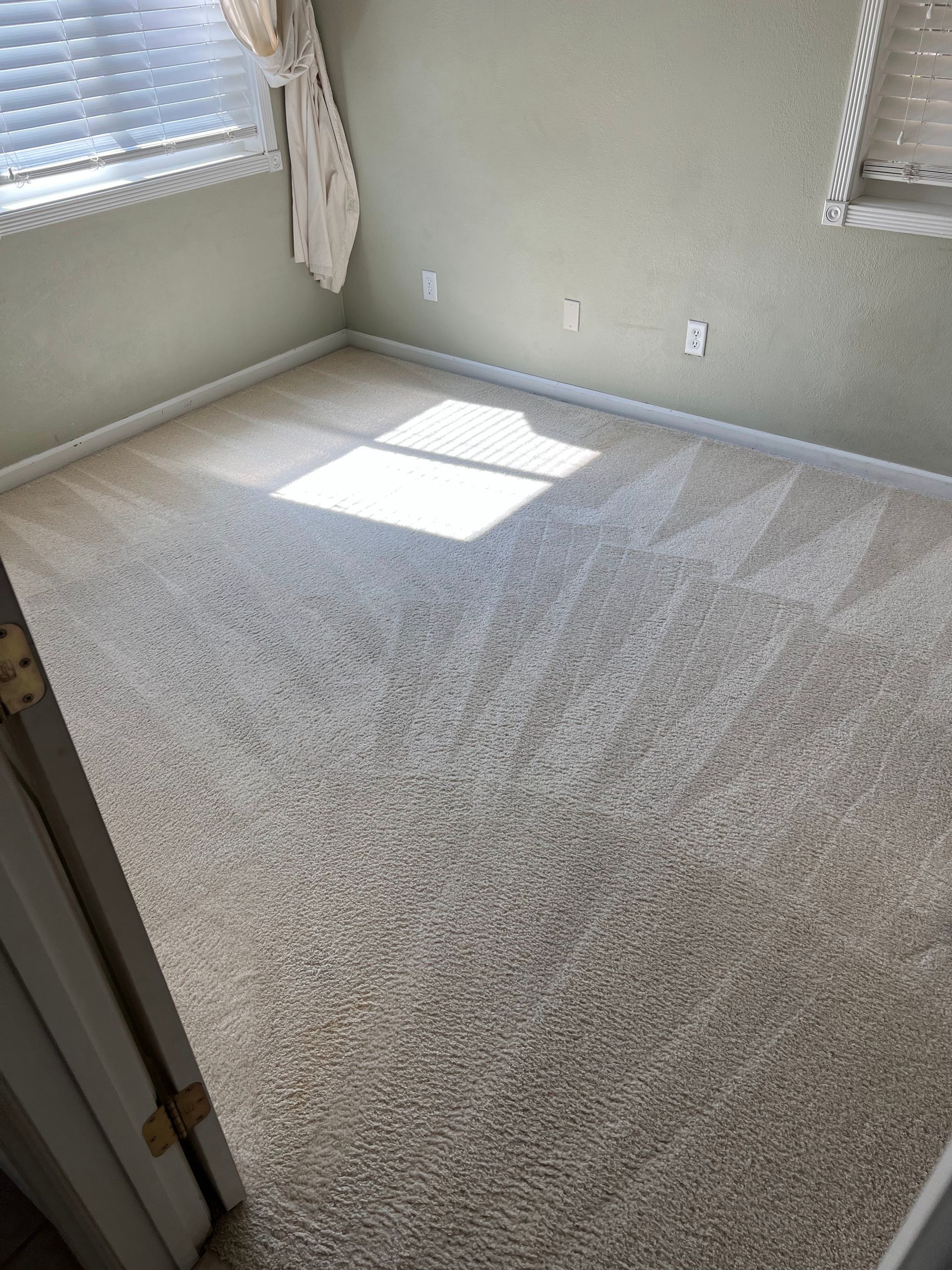 A bedroom with a carpeted floor and a window.
