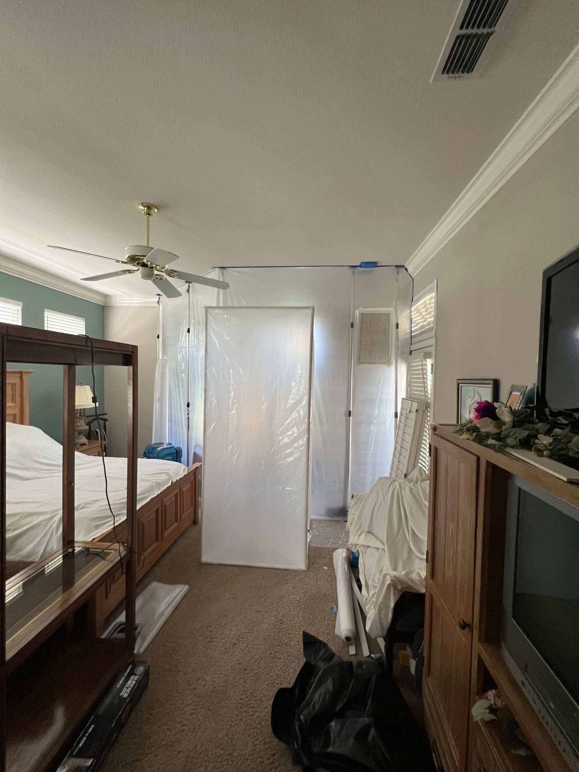 A bedroom with a ceiling fan and a tv