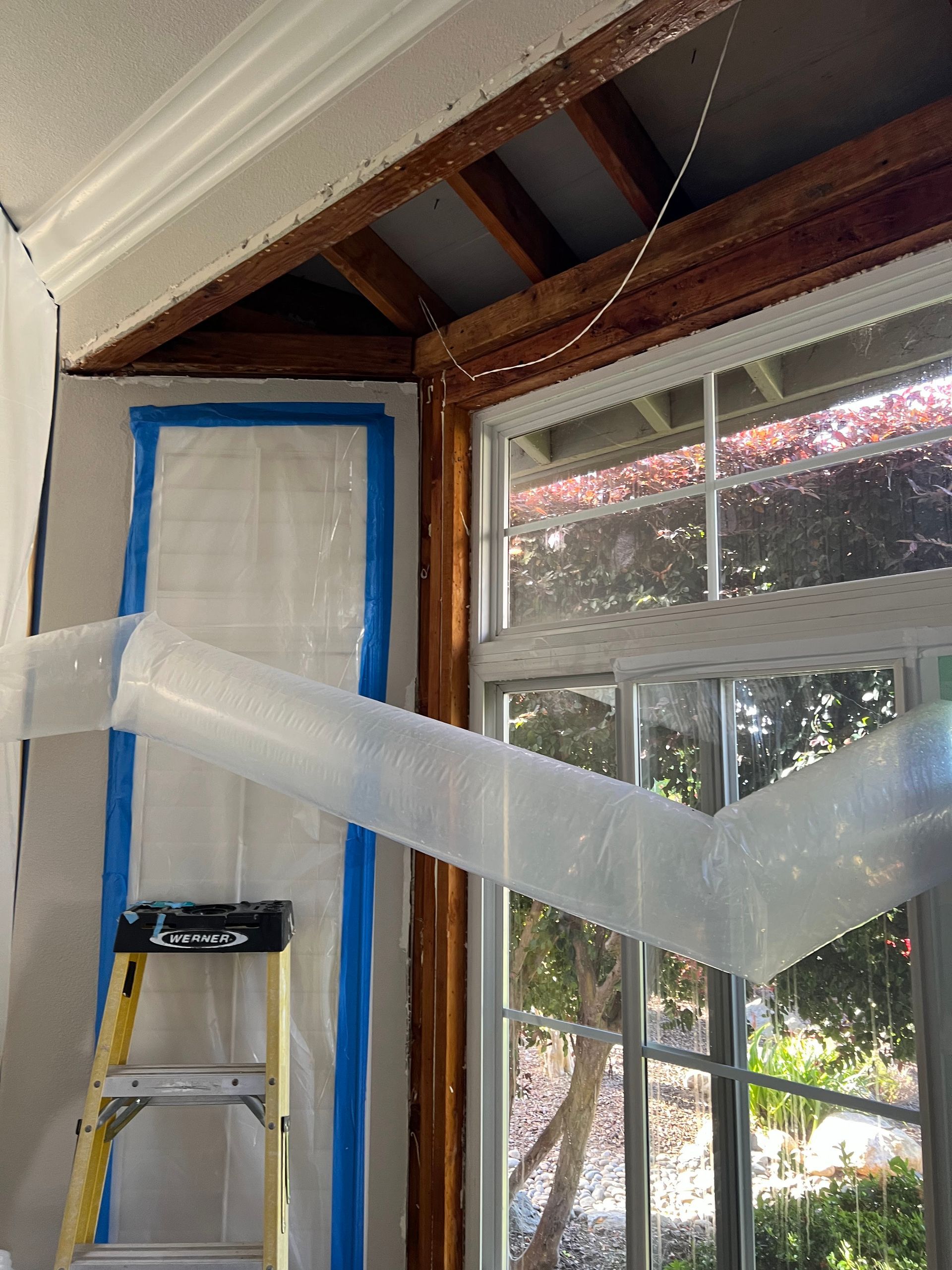 A room with a ladder and a window covered in plastic