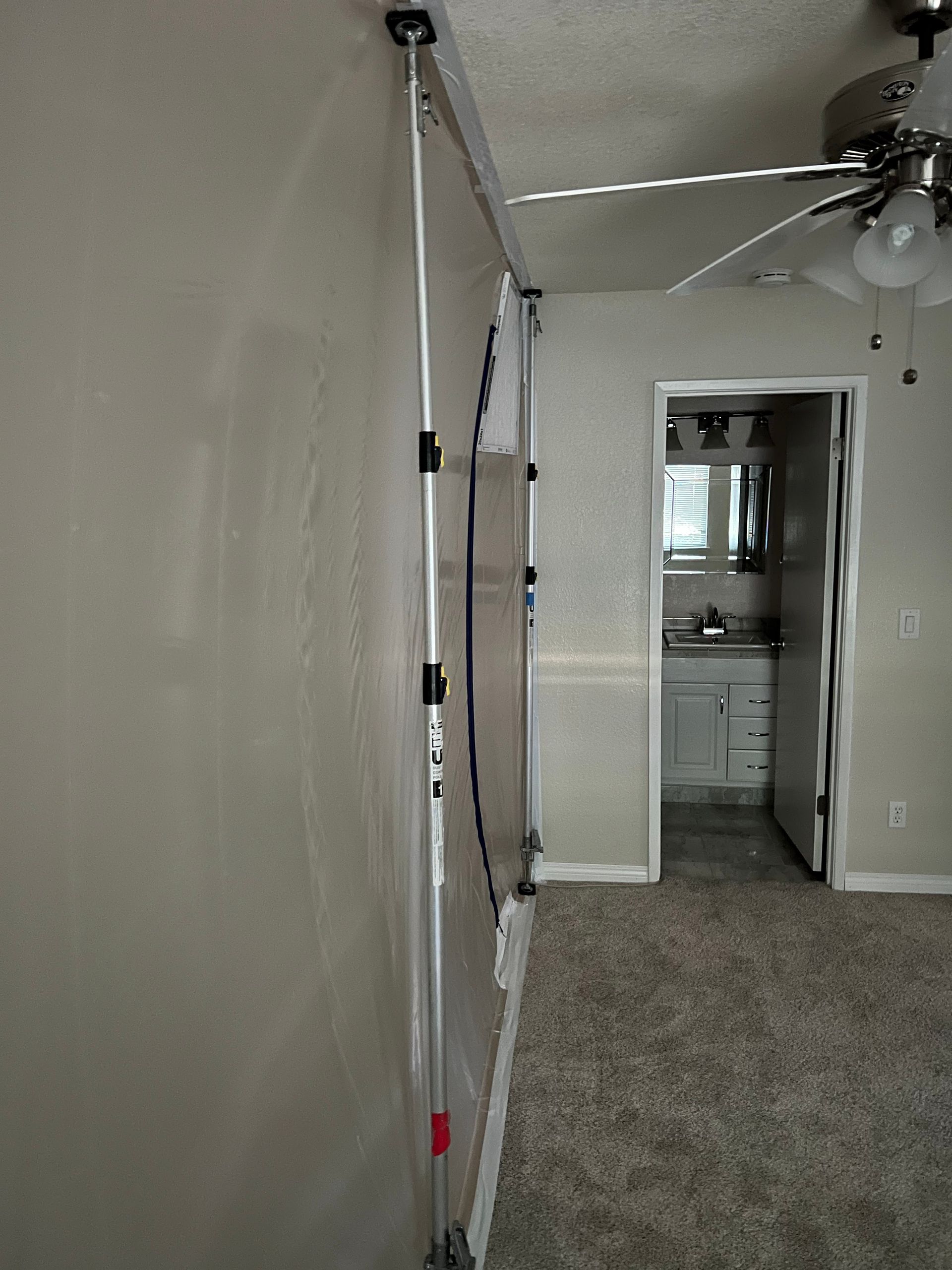 A room with a ceiling fan and a doorway leading to a bathroom.