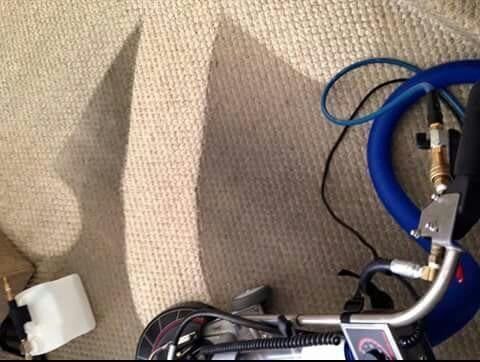 A carpet cleaning machine is sitting on top of a carpet.