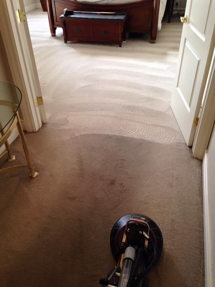 A vacuum cleaner is cleaning a carpet in a bedroom.