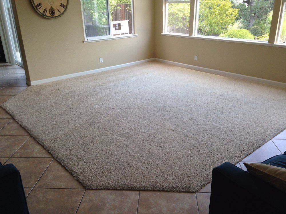 A living room with a large carpet and a clock on the wall