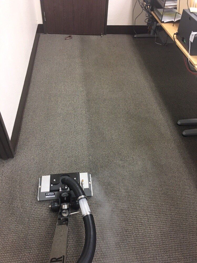 A vacuum cleaner is cleaning a carpet in an office.