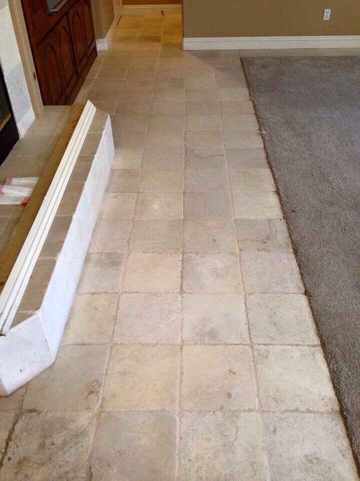 A living room with a tiled floor and a rug.
