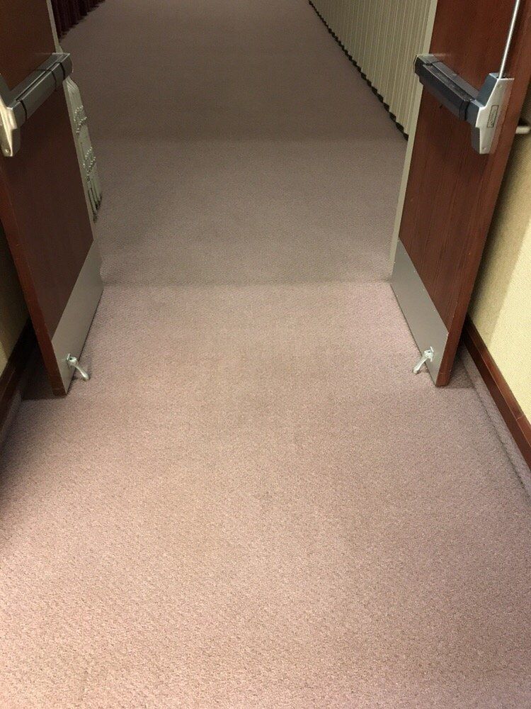 A hallway with two doors open and a carpeted floor.