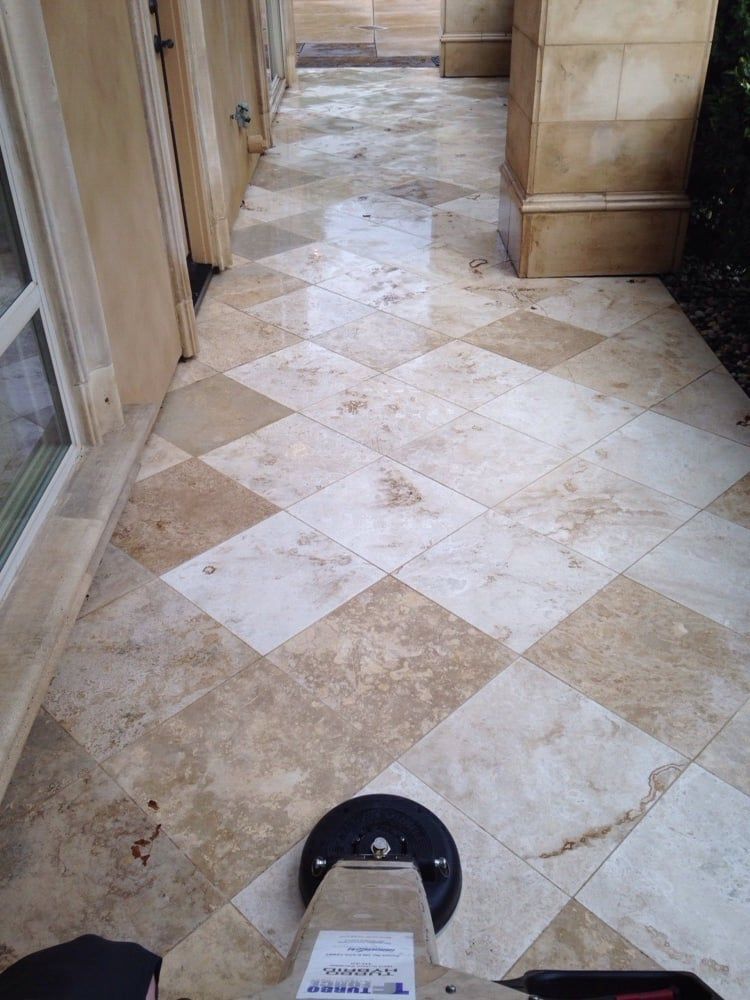 A person is cleaning a tile floor with a machine.