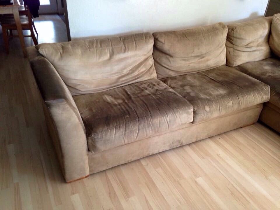A brown couch is sitting on a wooden floor in a living room.