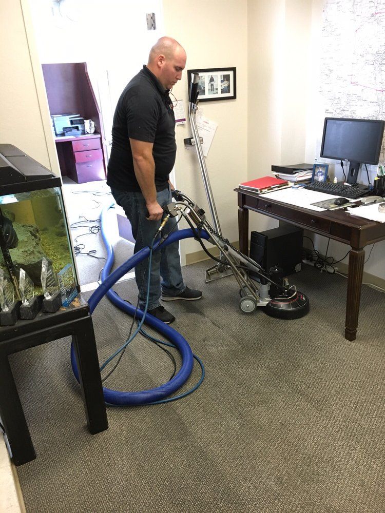 A man is using a vacuum cleaner to clean a carpet in an office.