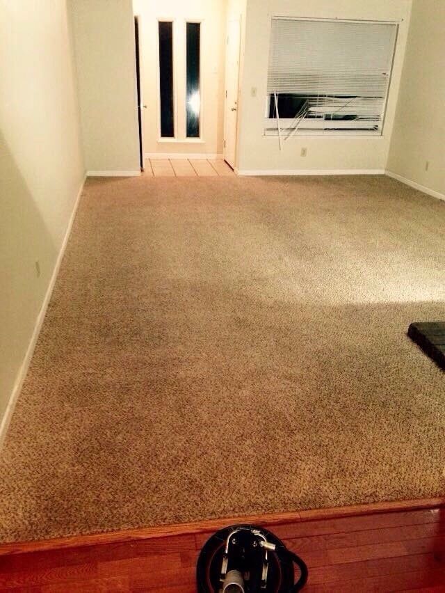 An empty living room with a vacuum cleaner on the floor.