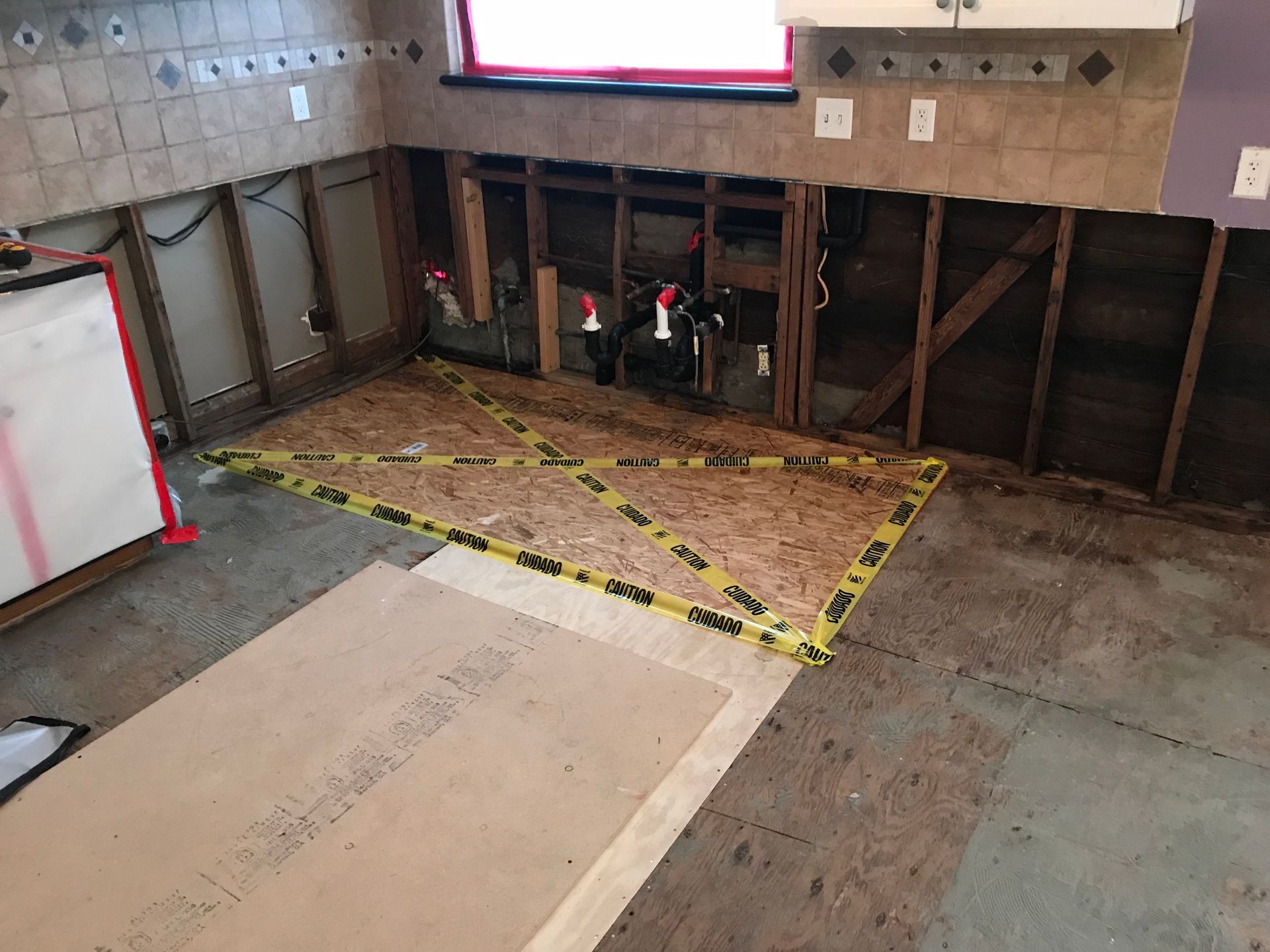 A kitchen under construction with a yellow tape around the floor.