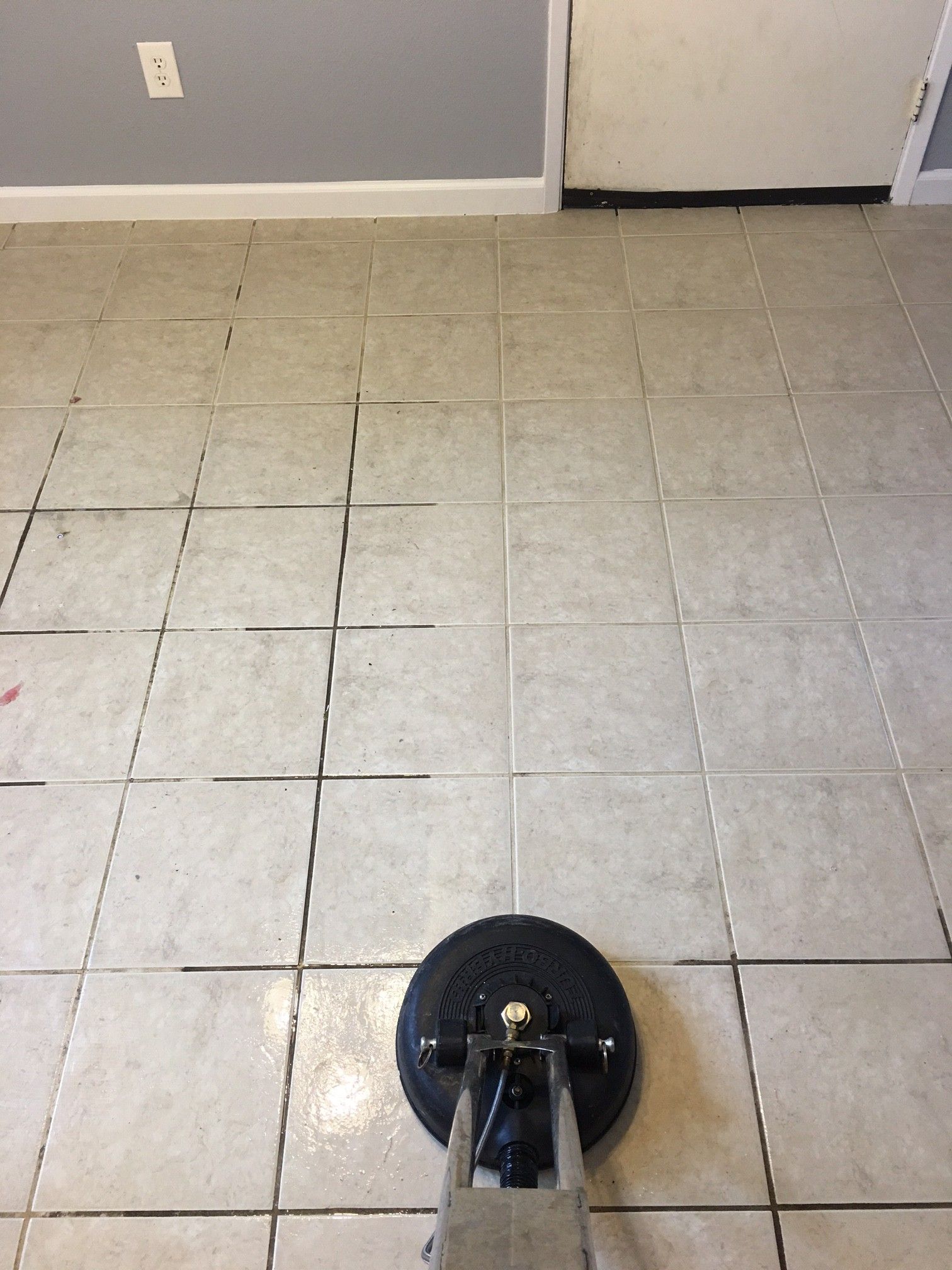 A tile floor is being cleaned with a machine.