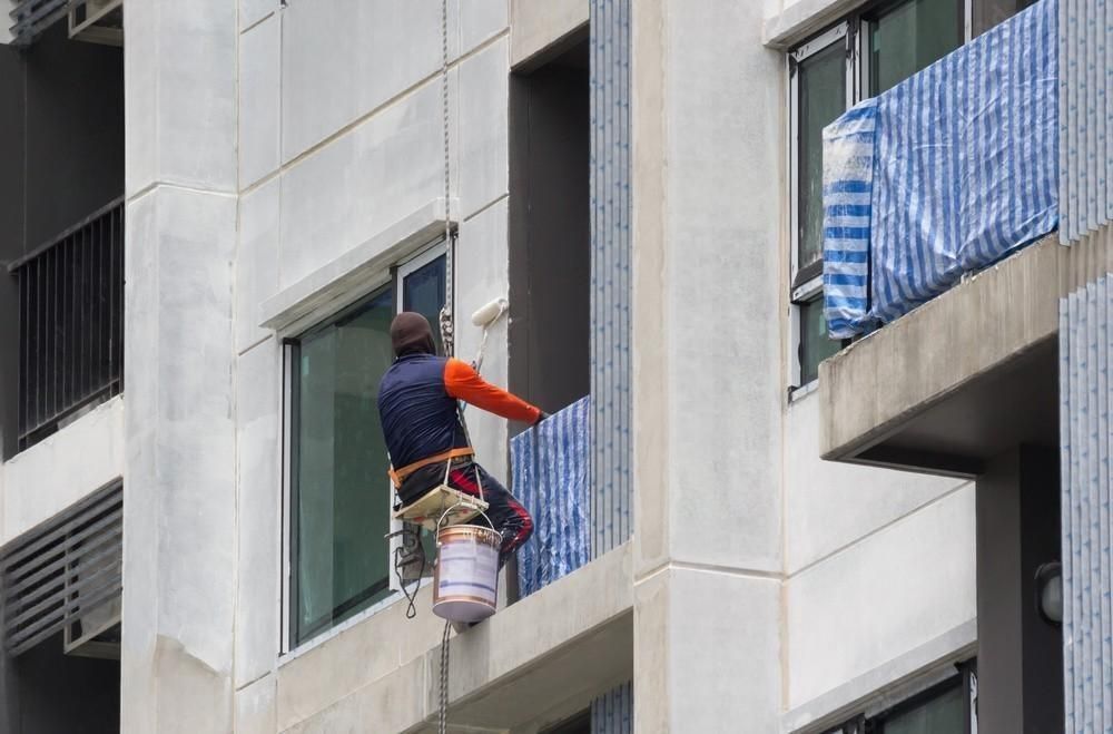 A man is painting a blue wall with a paint roller.